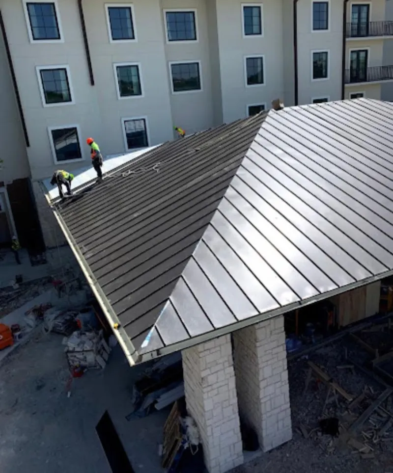 Crew installing standing seam metal roof panels on a commercial project in South Charleston